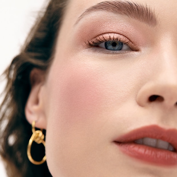 Close up of model eye showcasing defined brows and a natural, shimmery eye look